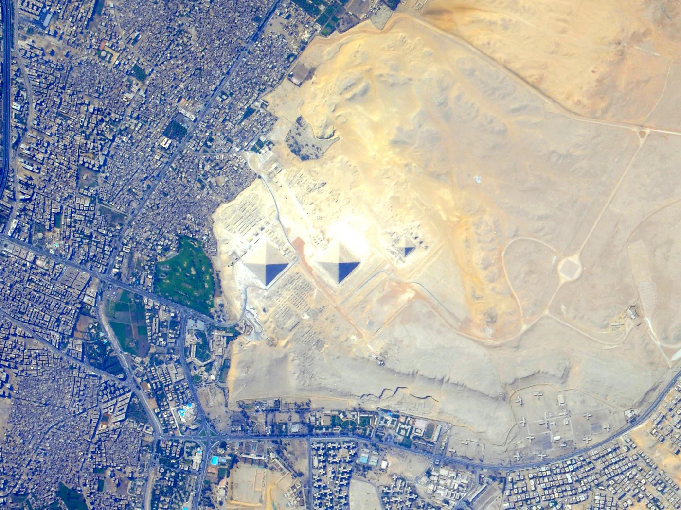 Satellite image of the Giza Plateau and the edge of Cairo, Egypt, showing the pyramids against the desert and the city