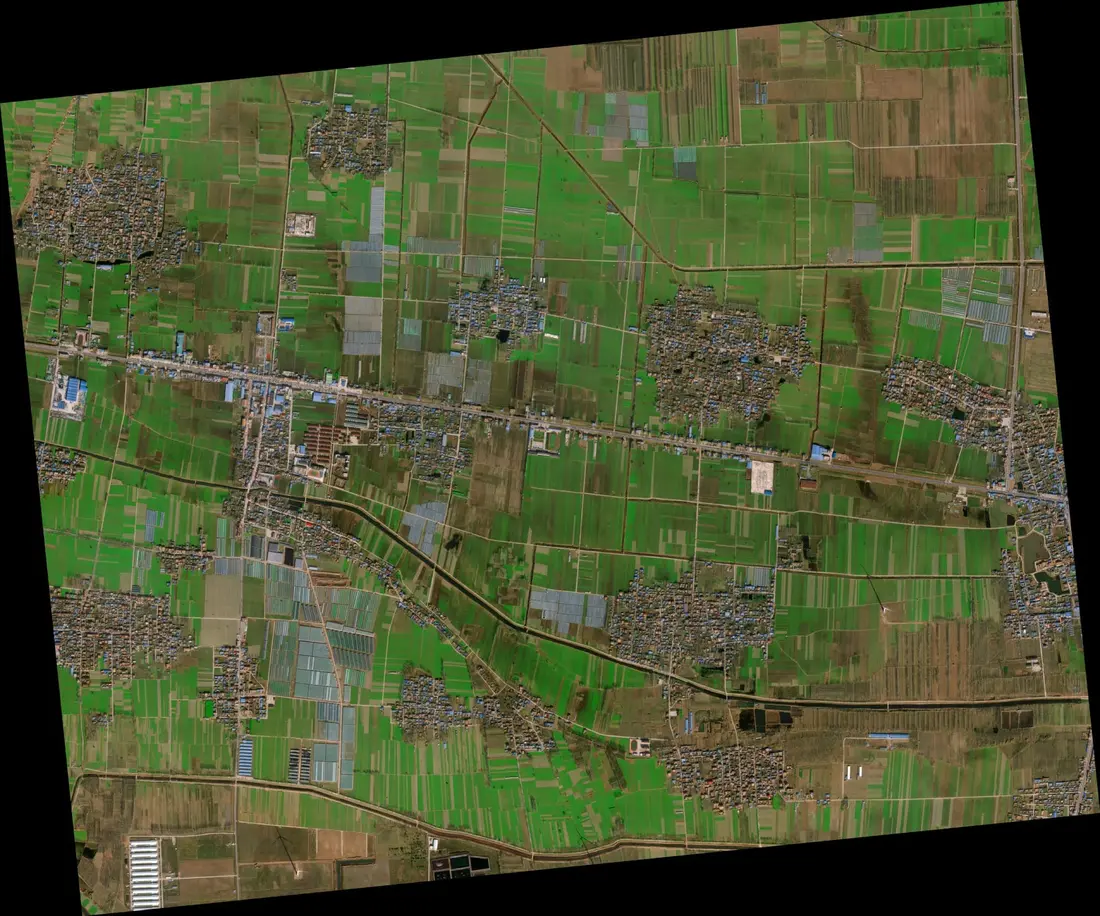 80cm high resolution satellite image of a river crossing in China showing a bridge, cargo ships, and dense urban blocks