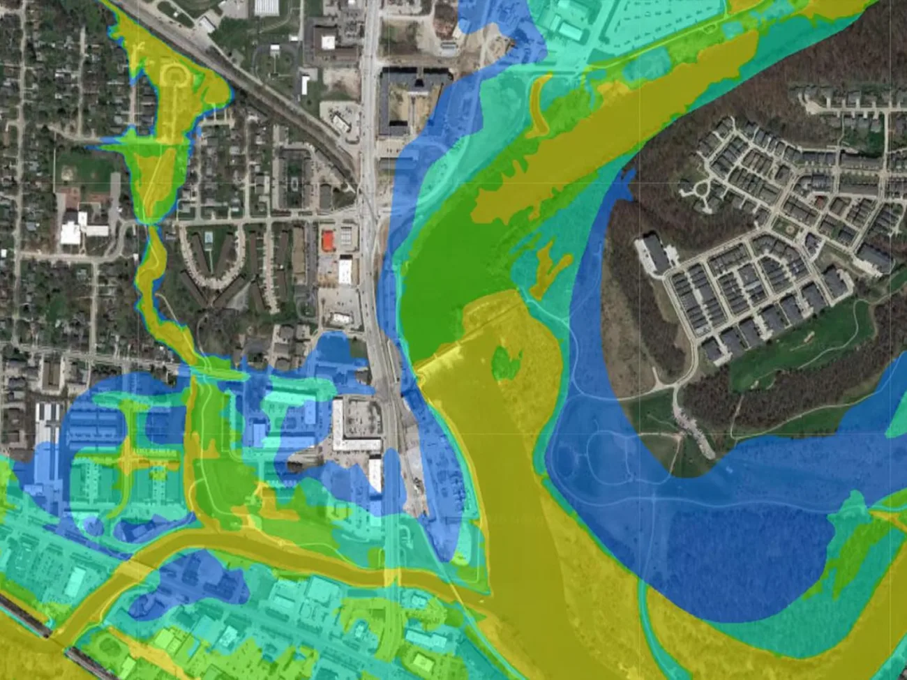 Color-coded flood inundation depth model over a populated area, showing water depth in graduated blue, teal, and yellow zones