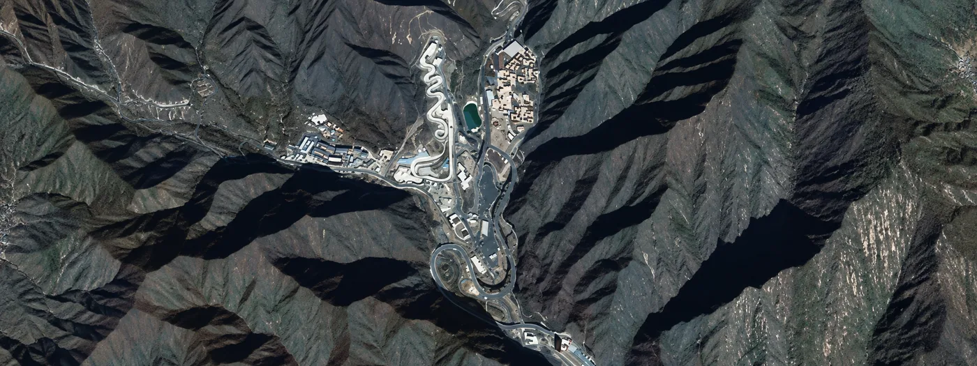 Satellite imagery of a remote facility and access roads across mountainous terrain