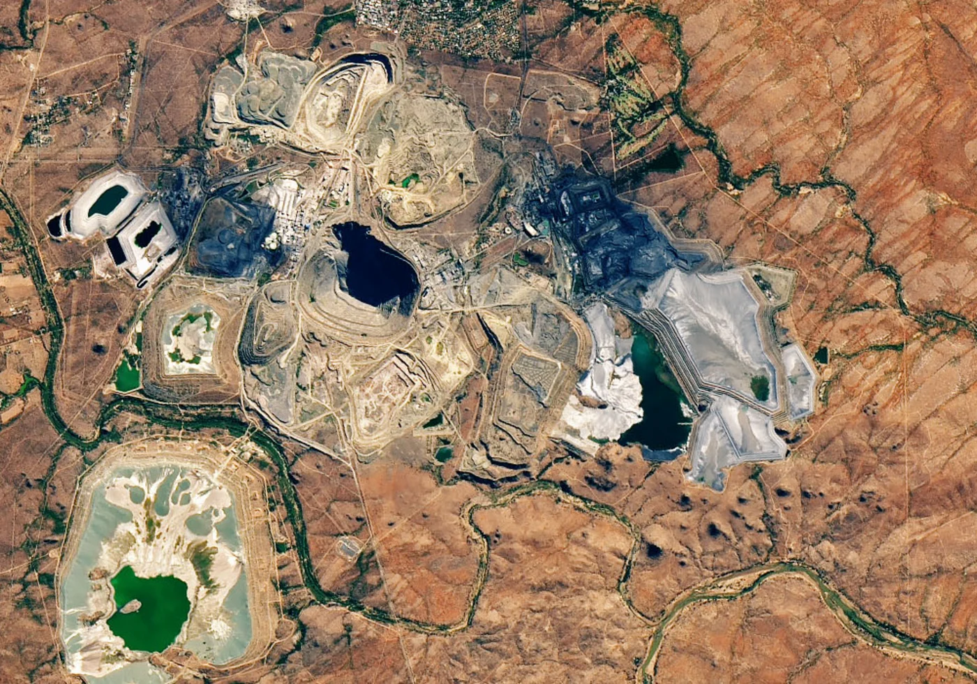 Landsat multispectral satellite image of an open-pit mine showing tailings ponds and exposed mineral surfaces