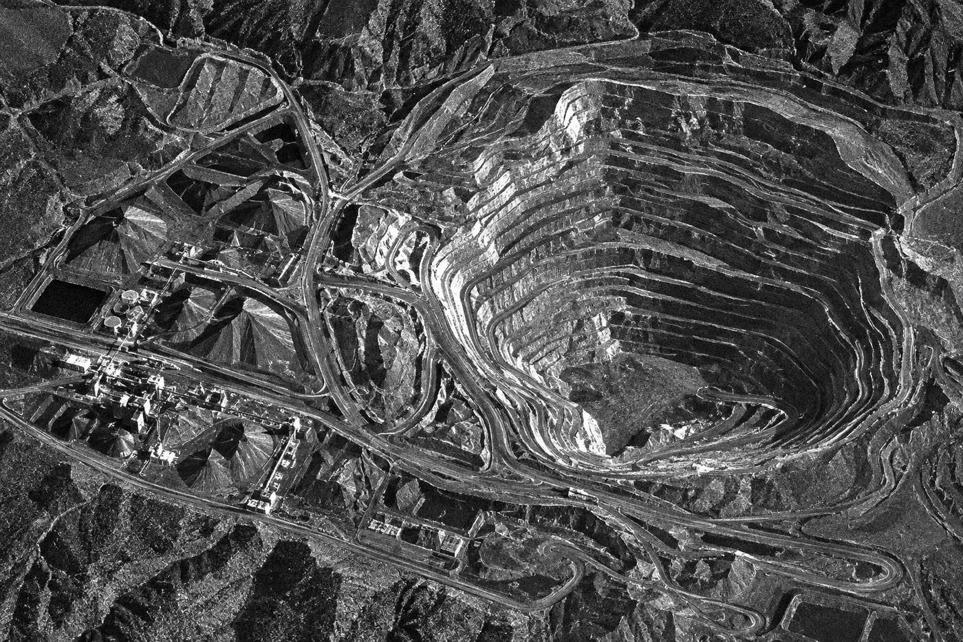 Grayscale synthetic aperture radar satellite image of an open-pit mine showing terraced bench levels